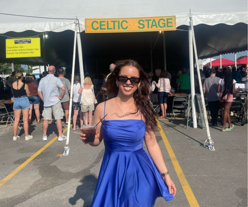 Rachel Walsh in blue dress holding a drink outside of the Celtic Tent at a festival