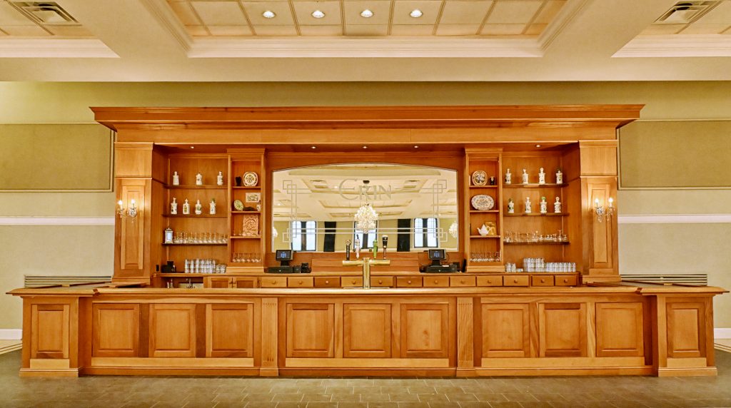 Picture of a large wooden bar with a mirror in the middle with the word 