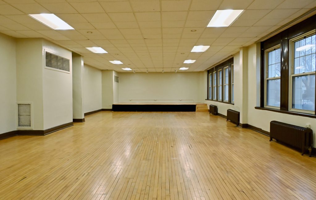 Picture of a small room with a small stage with windows and small radiators on the right